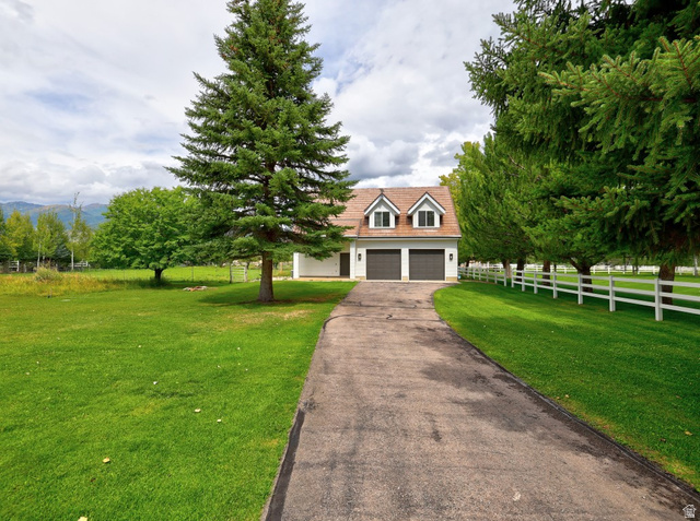 180 Farm Road Midway, UT 84049 - Photo 24 of 99 Expansive green lawn with mature trees, a paved driveway, and a white picket fence