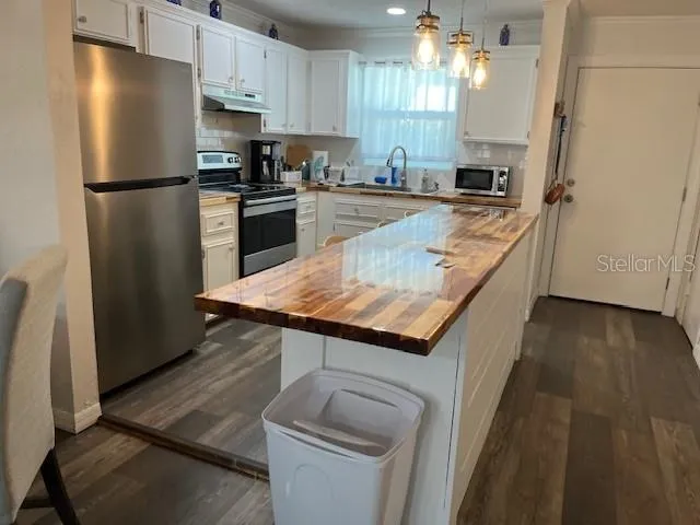 a kitchen with stainless steel appliances granite countertop a refrigerator a stove a sink dishwasher and microwave oven with wooden floor