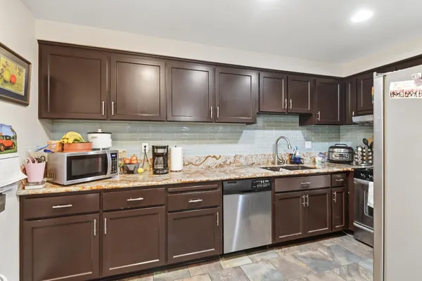 a kitchen with granite countertop stainless steel appliances a stove sink and cabinets
