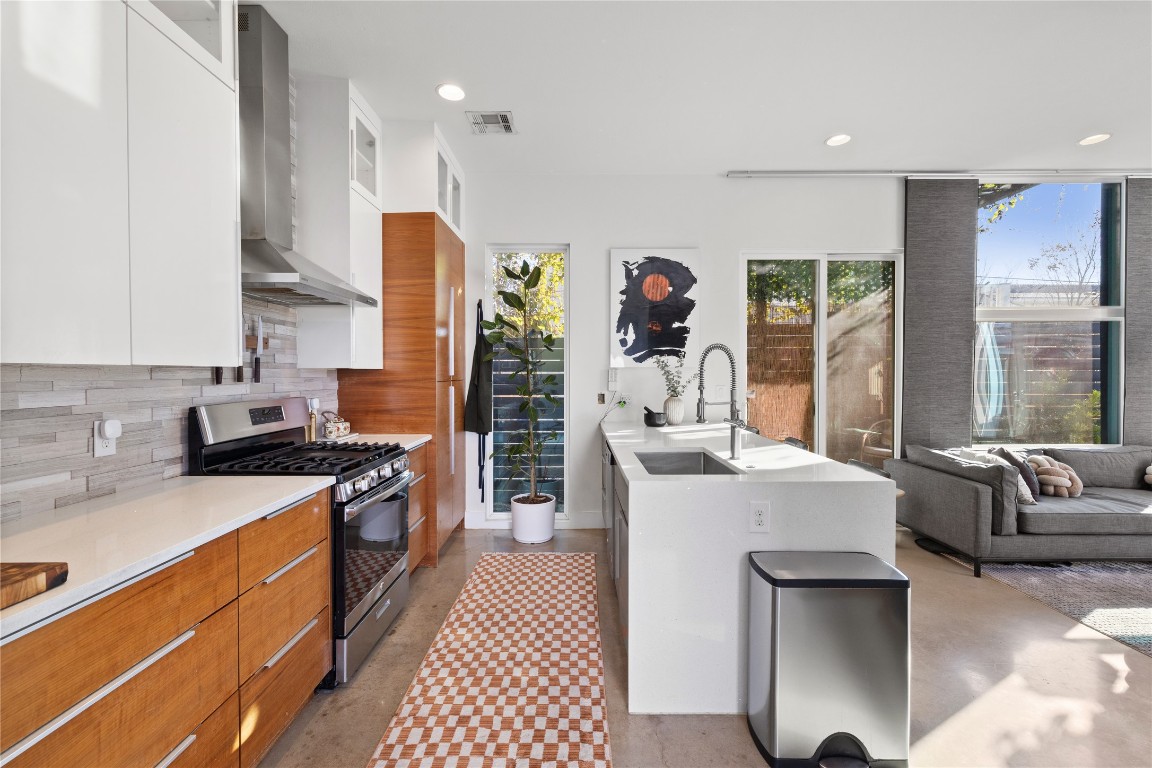 1904 East 17th Street, Unit B Austin, TX 78702 - Photo 5 of 34 a large kitchen with stainless steel appliances granite countertop a stove a sink dishwasher a dining table and chairs with wooden floor