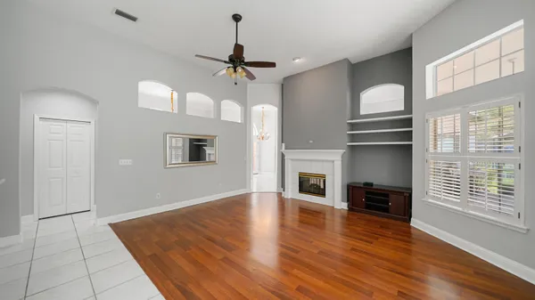 a view of empty room with wooden floor and fan