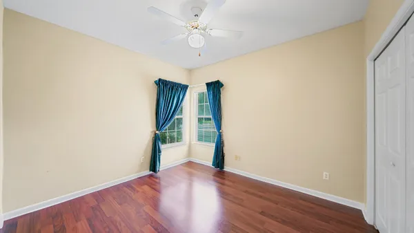 an empty room with wooden floor and a ceiling fan