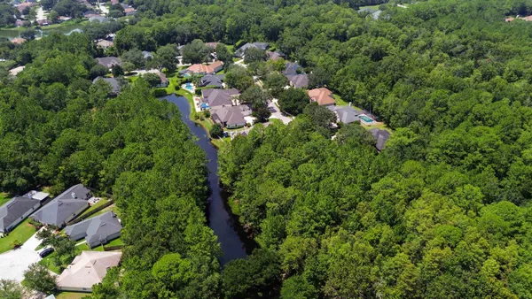 an aerial view of residential house with outdoor space and trees all around