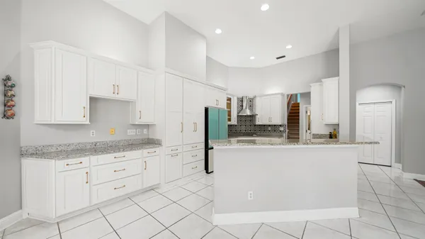 a kitchen with granite countertop a refrigerator and white cabinets