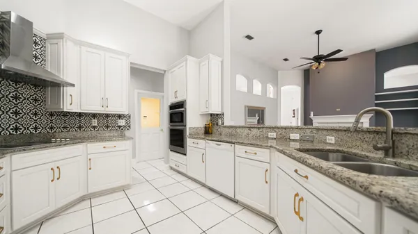 a kitchen with granite countertop white cabinets white appliances and sink