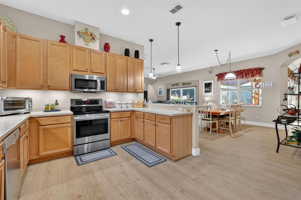 25517 Laurel Valley Road Leesburg, FL 34748 - Photo 15 of 56 a kitchen with stainless steel appliances granite countertop a stove top oven a sink a dining table and chairs with wooden floor