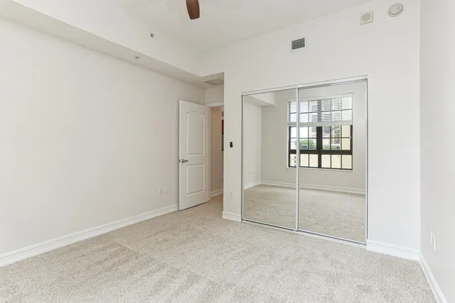 an empty room with chandelier fan and windows