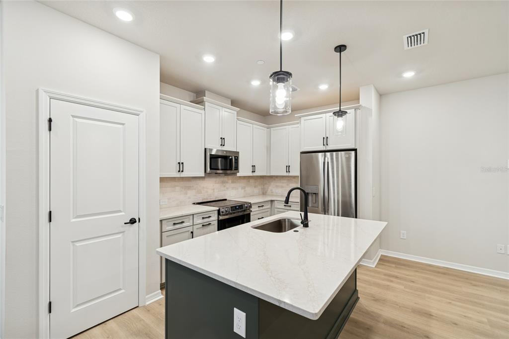 4317 Roush Avenue Orlando, FL 32803 - Photo 4 of 39 a kitchen with stainless steel appliances a refrigerator a sink dishwasher a stove and white cabinets with wooden floor