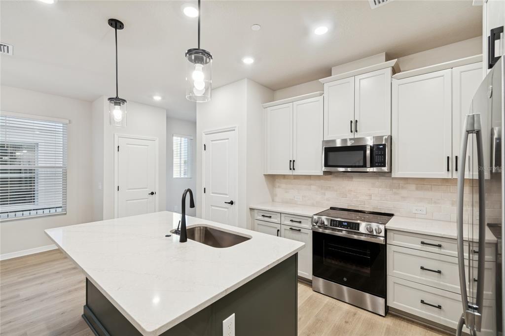 4317 Roush Avenue Orlando, FL 32803 - Photo 5 of 39 a kitchen with stainless steel appliances a sink a stove a refrigerator cabinets and wooden floor