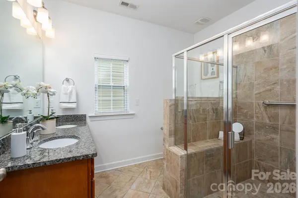 a bathroom with a granite countertop sink a mirror and shower