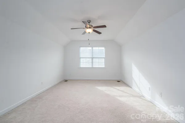 an empty room with windows and chandelier fan