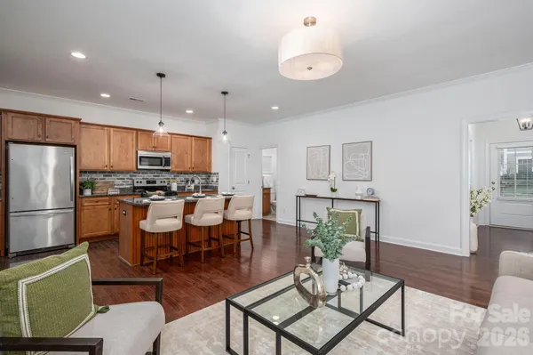a kitchen with stainless steel appliances kitchen island granite countertop a refrigerator a stove a microwave oven a dining table and chairs with wooden floor