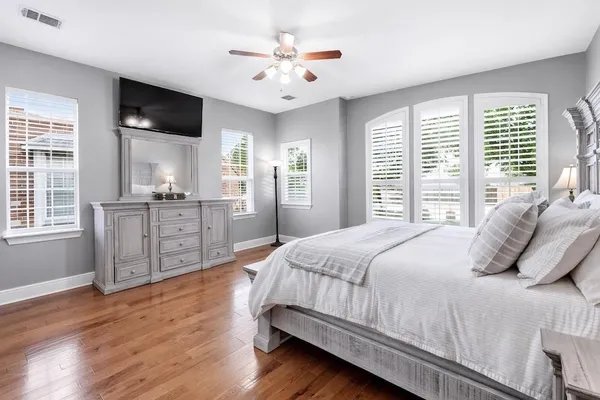 a bedroom with a large bed a flat tv screen and next to a window