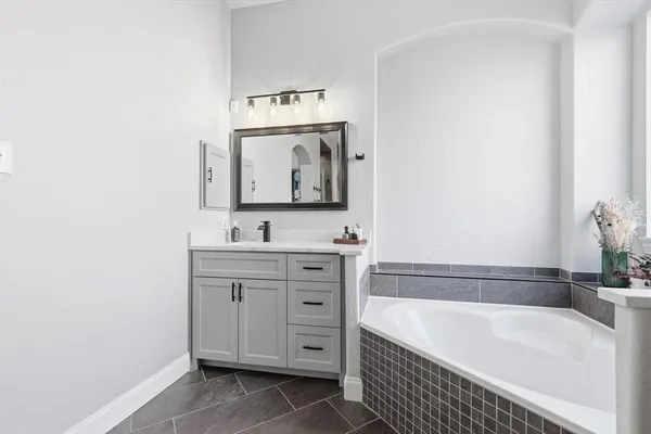 a bathroom with a tub sink and mirror