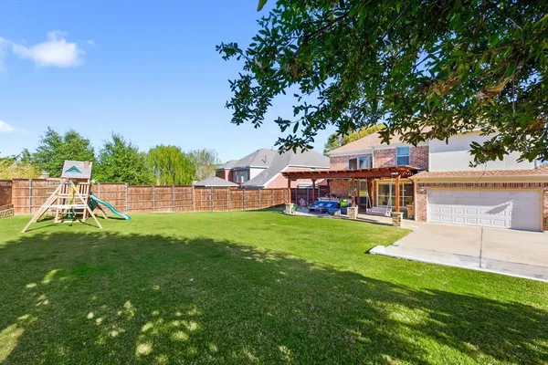 a view of backyard with table and chairs plants and large trees