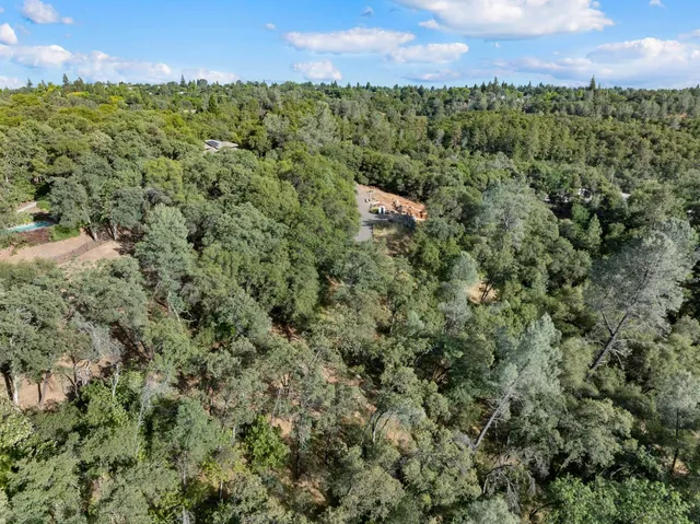 an aerial view of residential house with outdoor space and trees all around