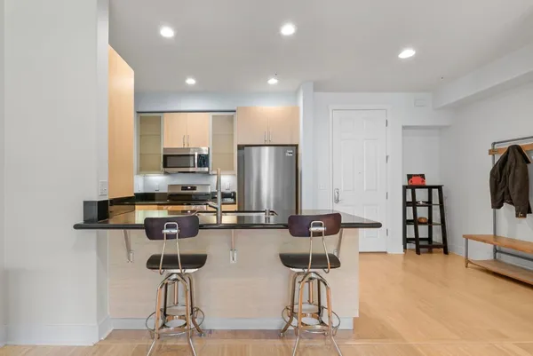a kitchen with stainless steel appliances kitchen island granite countertop a refrigerator and cabinets