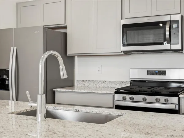 a kitchen with stainless steel appliances granite countertop a stove a microwave and a refrigerator