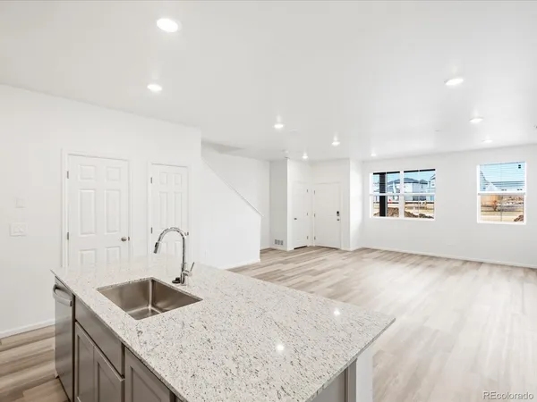 a kitchen with a sink dishwasher and a refrigerator with wooden floor