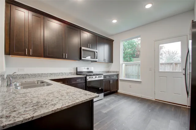 a kitchen with granite countertop cabinets stainless steel appliances a sink and window