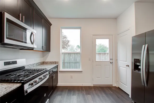 a kitchen with stainless steel appliances granite countertop a stove a refrigerator and a microwave