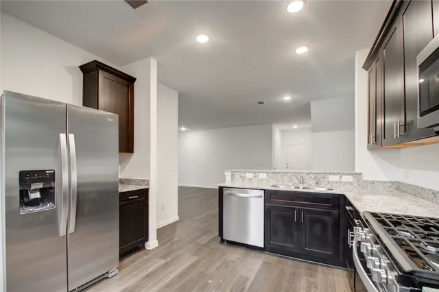 a kitchen with stainless steel appliances granite countertop a stove a sink and a refrigerator