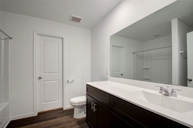 a bathroom with a granite countertop toilet a sink and a mirror