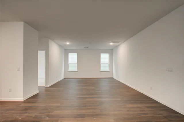 a view of an empty room with wooden floor and window