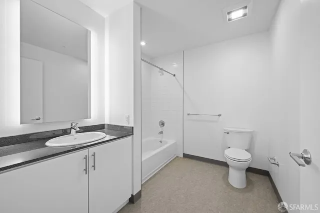 a bathroom with a granite countertop sink a toilet and a large mirror
