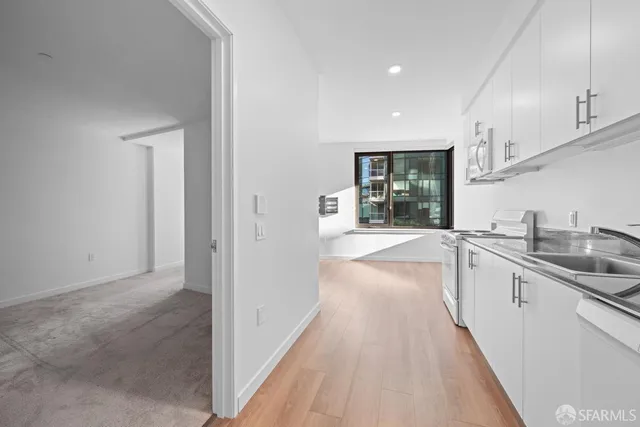 a view of a kitchen with a sink and dishwasher with white cabinets
