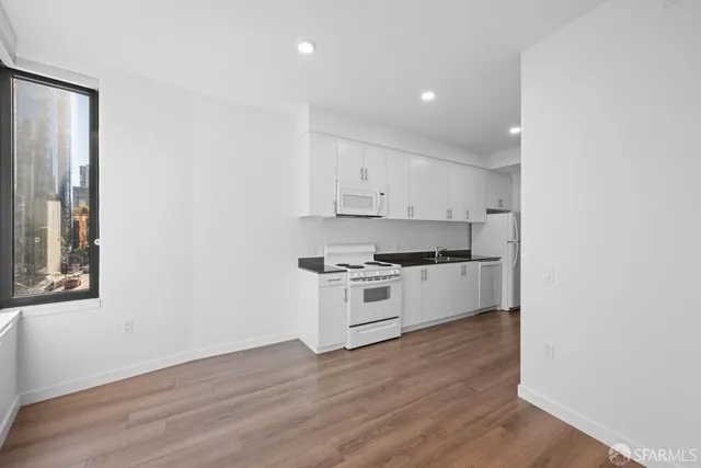 a kitchen with granite countertop white cabinets and white appliances