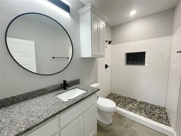 a bathroom with a granite countertop sink a mirror and a toilet