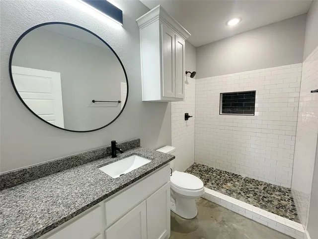 a bathroom with a granite countertop sink a mirror and a toilet