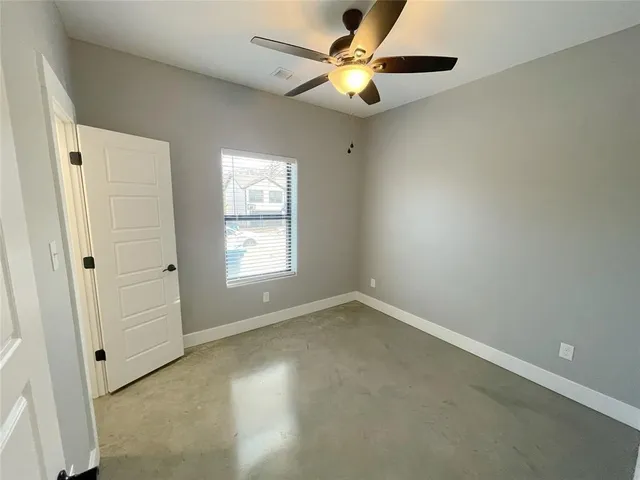 an empty room with a window and a fan