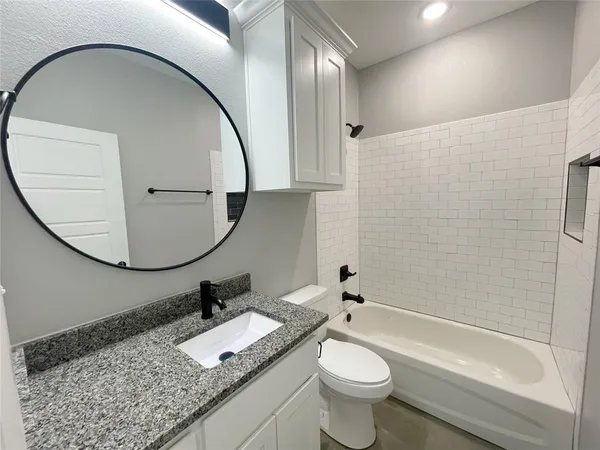 a bathroom with a granite countertop toilet a sink and a mirror