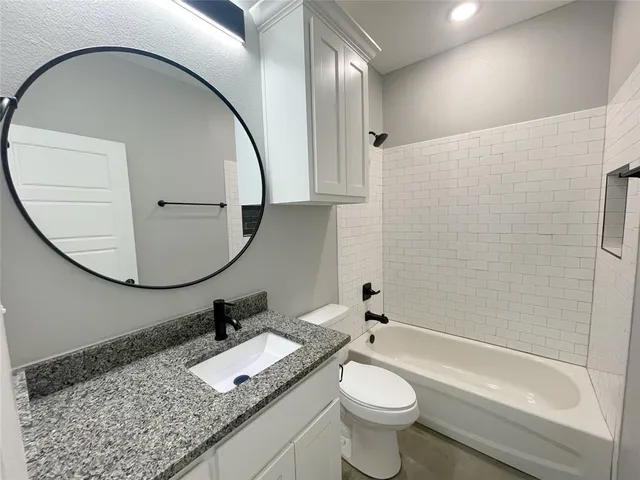 a bathroom with a granite countertop toilet a sink and a mirror