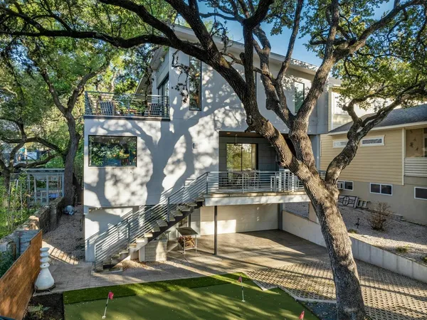 a view of house with yard outdoor seating and covered with trees