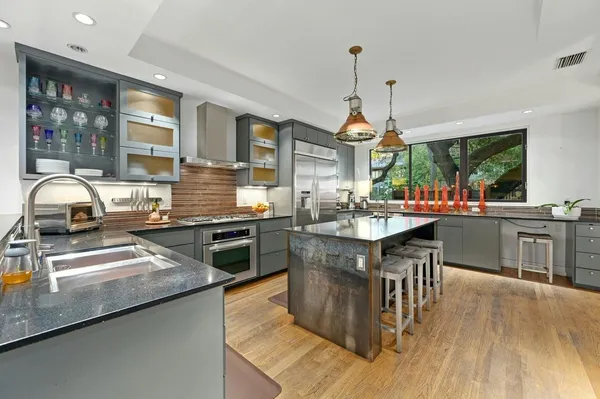 a kitchen with stainless steel appliances granite countertop a sink a stove and a wooden floors