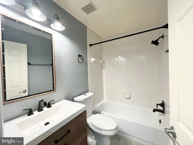 a bathroom with a bathtub shower sink mirror vanity and toilet