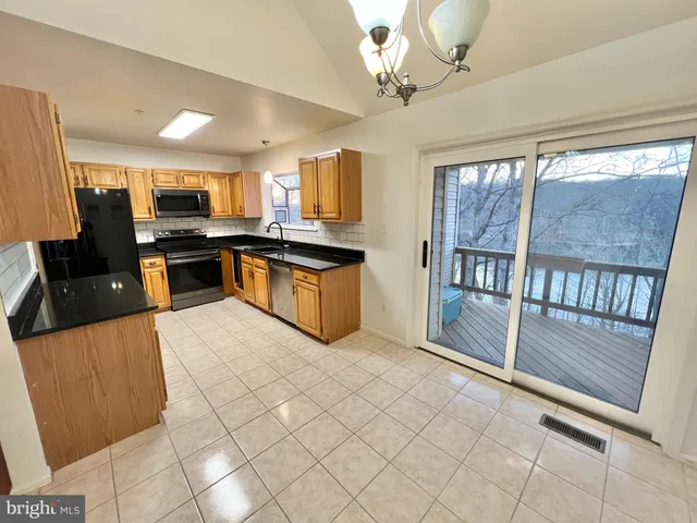 a kitchen with stainless steel appliances granite countertop a stove top oven a sink a counter space and cabinets