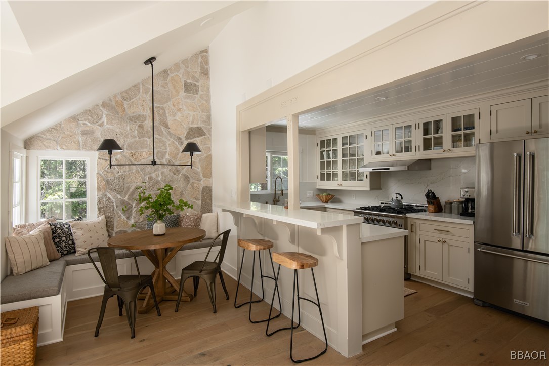 920 Oak Road Lake Arrowhead, CA 92385 - Photo 7 of 28 a kitchen with stainless steel appliances granite countertop a stove a refrigerator a dining table and chairs with wooden floor