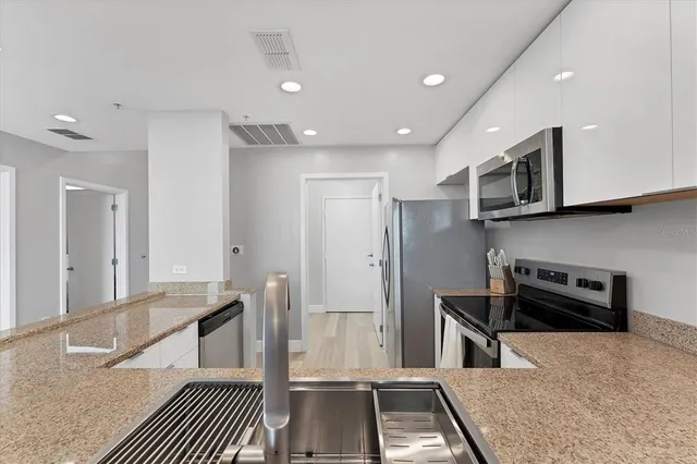 a kitchen with stainless steel appliances granite countertop a refrigerator and a stove top oven