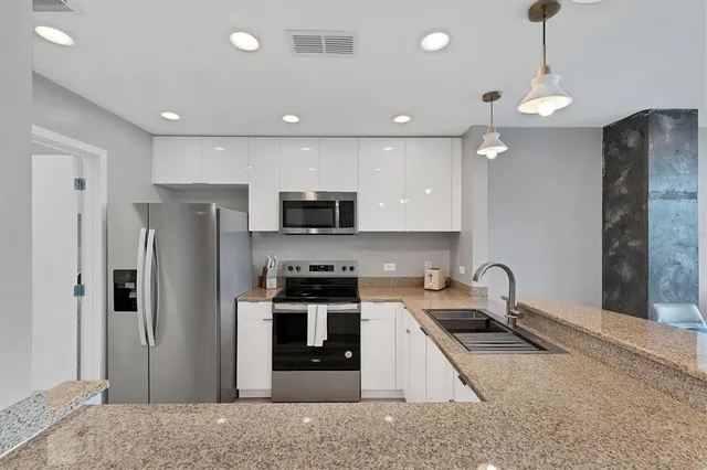 a kitchen with stainless steel appliances granite countertop a refrigerator a stove a sink and a microwave