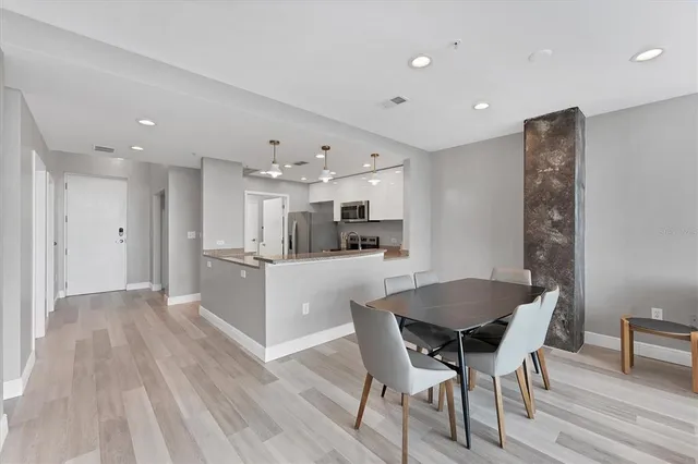 a kitchen with stainless steel appliances kitchen island granite countertop a table chairs sink and cabinets
