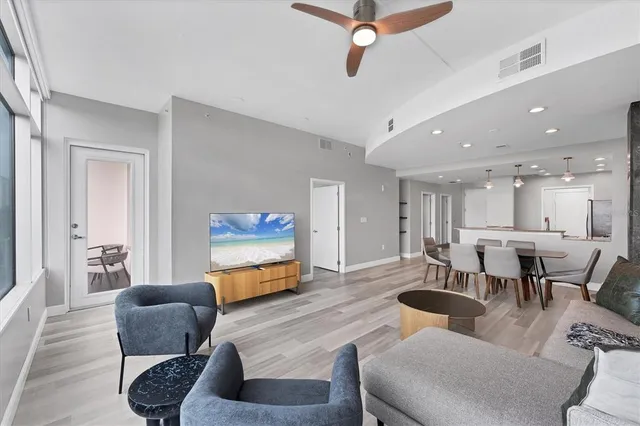 a living room with furniture and a dining table with projector the kitchen