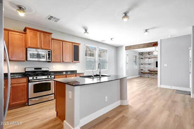 a kitchen with stainless steel appliances granite countertop a sink stove and wooden cabinets
