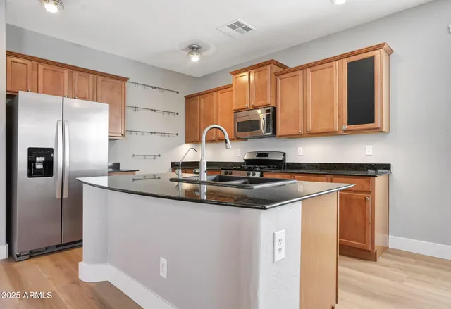 a kitchen with stainless steel appliances granite countertop a sink stove refrigerator and cabinets