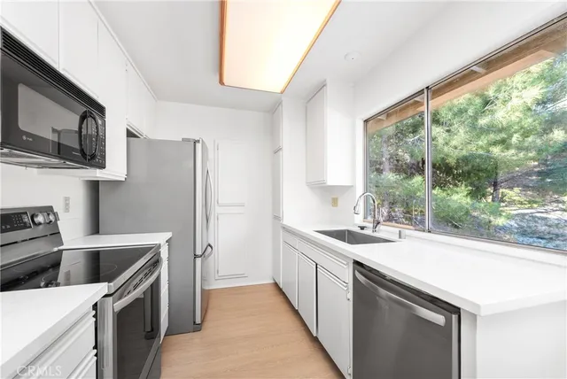 a kitchen that has a sink a stove top oven a refrigerator cabinets and a window