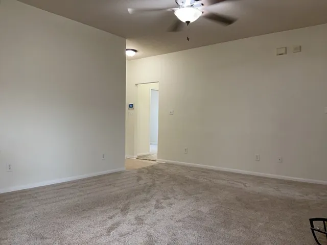 an empty room with a ceiling fan and a window