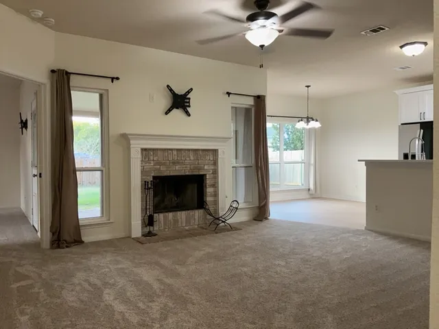 a view of a livingroom with a fireplace a ceiling fan and front door